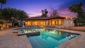 Resort-style pool and spa with glowing patio at sunset