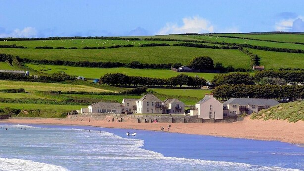 A coastal area with a beach, houses, and rolling green hills in the background. - 3 Bed in Braunton (oc-87112) (Croyde)