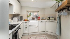 A kitchen with white cabinets, a black stove, a microwave, and a window with a view. - 2 Bed in Warkworth (oc-coq123) (Warkworth)