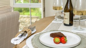 A dining table with a plate of dessert, two glasses of white wine, and a bottle of wine. - 2 Bed in Warkworth (oc-coq123) (Warkworth)