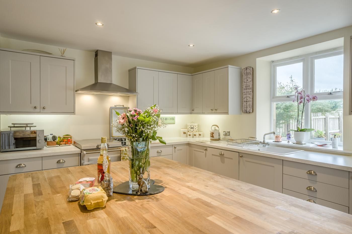 A modern kitchen with a large island, white cabinetry, and a window providing natural light.