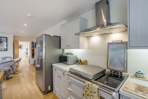 A modern kitchen with stainless steel appliances, a built-in oven, and a microwave. - 3 Bed in Scremerston (oc-w42466) (Scremerston)