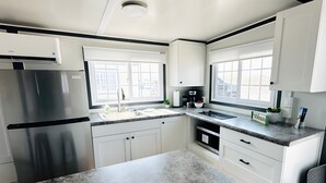 Una cocina moderna con armarios blancos, encimeras de granito, un refrigerador de acero inoxidable y un ventanal que proporciona luz natural.