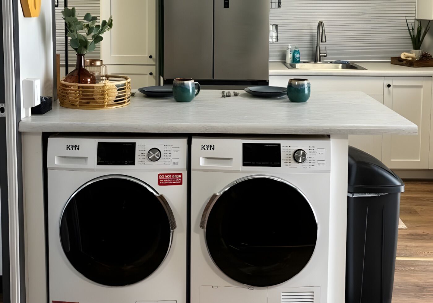 A laundry area with two front-loading washing machines, a sink, and a trash bin.