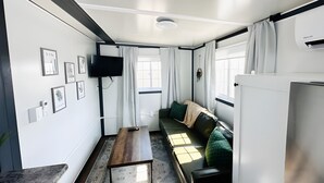 Un espacio habitable compacto con sofá, mesa, televisor y cuadros en las paredes.