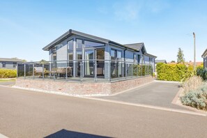 A modern building with large windows, a covered outdoor seating area, and a brick base. - 2 Bed in Burnham Market (oc-s42081) (Burnham Market)