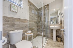 A modern bathroom with a glass shower enclosure, a toilet, a sink, and a framed plant on the wall. - 2 Bed in Burnham Market (oc-s42081) (Burnham Market)