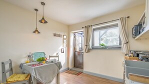 A cozy kitchen with a dining area, wooden flooring, and pendant lighting. - 1 Bed in Heacham (oc-c40224) (Heacham)