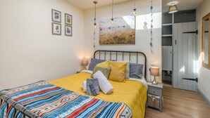 A bedroom with a bed, bedside lamps, a skylight, a painting, and a wardrobe. - 1 Bed in Heacham (oc-c40224) (Heacham)