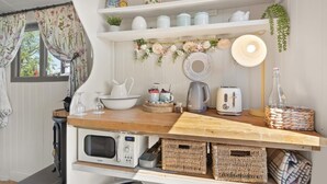 A kitchen with a wooden countertop, white cabinets, a microwave, a toaster, and various kitchenware.