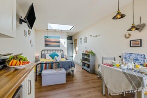 Ein gemütlicher Raum mit Bett, Esstisch, Küchenzeile und großem Fenster.