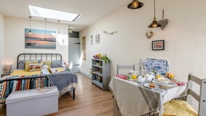 Ein Schlafzimmer mit Bett, Nachttisch und Blick auf den Strand durch ein Oberlicht.