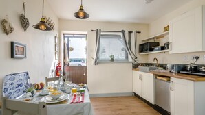 Eine kompakte Küche mit Esstisch, gedecktem Frühstückstisch, einer Mikrowelle und einem kleinen Fenster mit Vorhängen.
