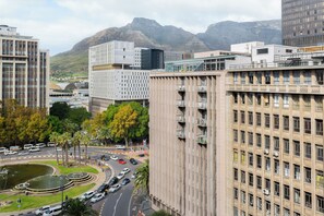 A cityscape with modern buildings, a roundabout, and a mountainous backdrop. - Charlie and the Chairman | Modern CBD Apartment (Cape Town)