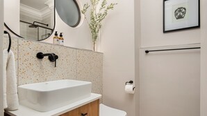 Une salle de bain avec un lavabo blanc, un meuble en bois et des toilettes.