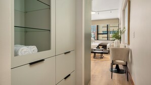 Une chambre d’hôtel moderne avec un grand miroir, un canapé, un fauteuil et une petite table.