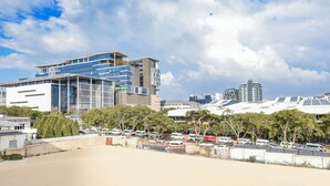 Un bâtiment moderne à plusieurs étages, doté de grandes fenêtres et d’un parking où sont stationnées plusieurs voitures.