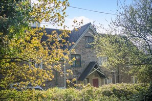 A stone building with a steeply pitched roof, a red door, and a small porch. - 1 Bed in Ashprington (oc-h41748) (Ashprington)