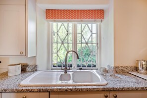 A kitchen with a double sink, a window with a diamond pattern, and a kitchen counter with a patterned backsplash. - 1 Bed in Ashprington (oc-h41748) (Ashprington)