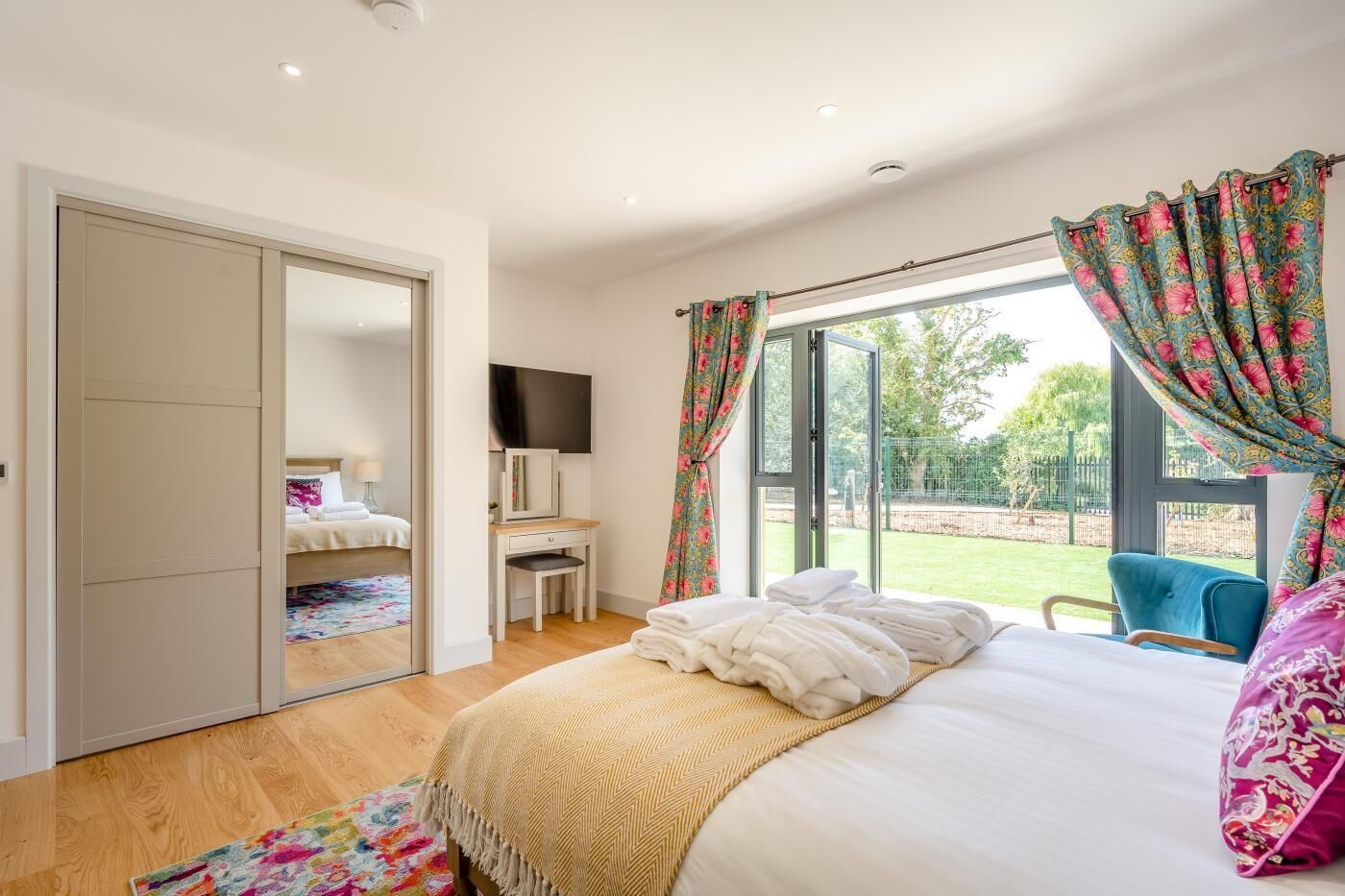Un dormitorio con cama, escritorio, televisión y vistas al exterior.