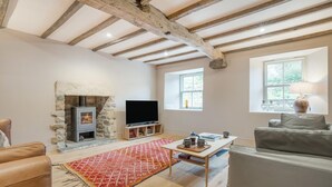 Ein Wohnzimmer mit Kamin aus Stein, einem Flachbildfernseher, einer Couch, einem Couchtisch und einem Fenster mit Blick.