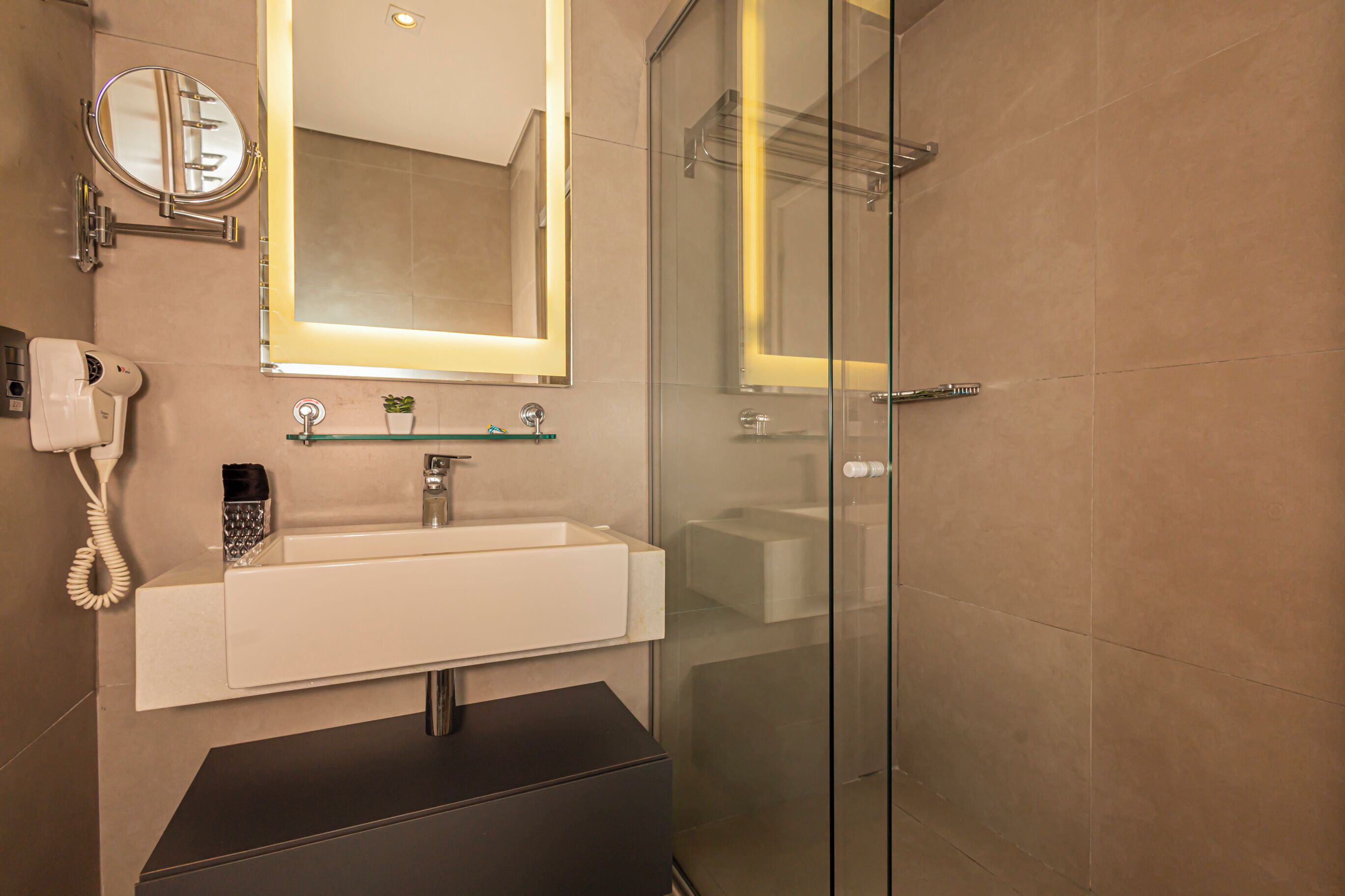 Une salle de bain moderne avec une douche à parois de verre, un lavabo blanc avec un miroir et un téléphone.