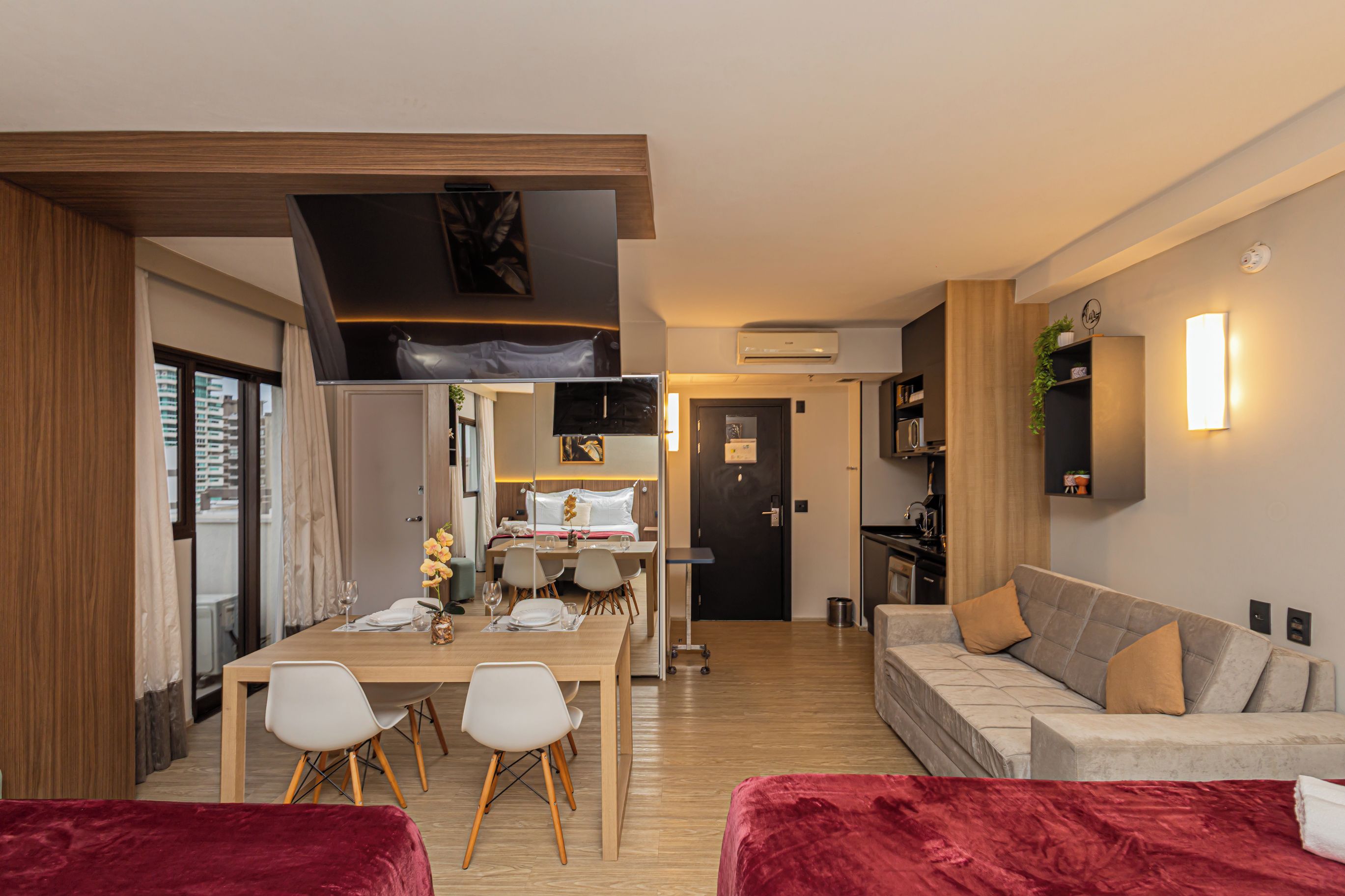 Ein modernes Hotelzimmer mit Essbereich, einer Couch und einem roten Samtstuhl.