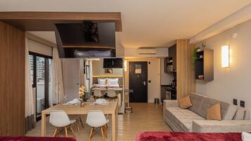 Ein modernes Hotelzimmer mit Essbereich, einer Couch und einem roten Samtstuhl.