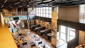A spacious restaurant with high ceilings, wooden flooring, and a variety of seating options including tables and booths.