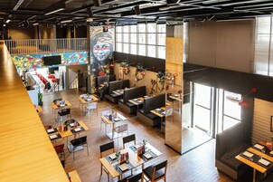 Un restaurante espacioso con techos altos, piso de madera y diversas opciones de asientos, como mesas y cabinas.