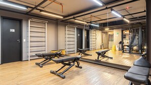 A gym with exercise equipment, a large mirror, and wooden flooring.