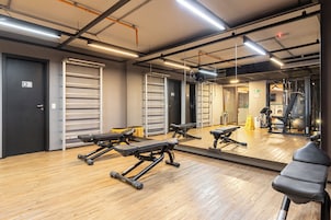 Un gimnasio con equipo de ejercicio, un espejo grande y suelo de madera.