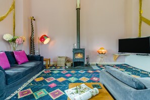 Ein Wohnzimmer mit einer Couch, einem Fernseher, einem Kamin und einem gemusterten Teppich.