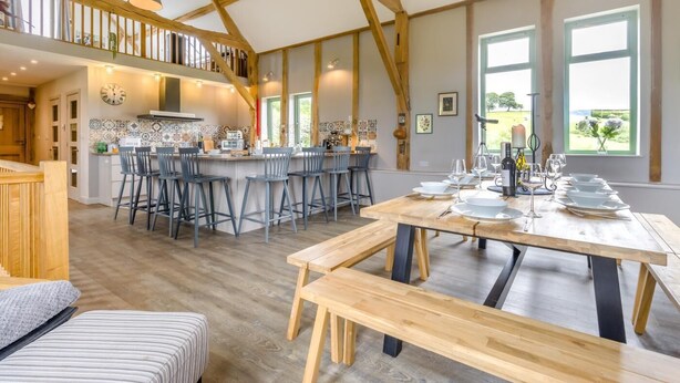 A spacious kitchen with a central island, a dining area with a long table, and a loft bedroom with a wooden ceiling. - 4 Bed in Beguildy (oc-t41741) (Beguildy)