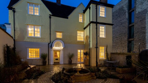 A two-story house with a central entrance, a small garden with a fountain, and a brick building to the right. - 2 Bed in Oxford (oc-s41047) (Oxford)