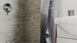 A bathroom with a shower curtain, a wall-mounted faucet, and a sink.