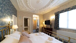 Habitación de hotel con una cama grande, televisión, baño y vistas al exterior.