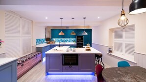 Una cocina moderna con una isla central, iluminación colgante y vista al área de comedor.