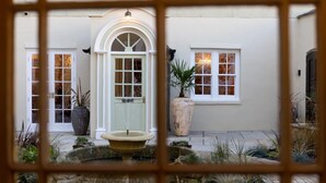 Un patio con una fuente, una planta grande en maceta y un edificio con ventanas de arco y una puerta.