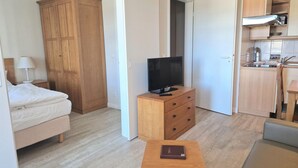 Makuuhuoneessa on sänky, puinen vaatekaappi, televisio, joka on sijoitettu puiseen lipastoon, pieni pöytä, jonka päällä on kirja, sekä pieni keittotila, jossa on kaappeja ja pesuallas.