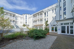 A multi-story building with balconies, a greenhouse, and a gravel courtyard. - Fantastisches Studio im Seepark Sellin mit Balkon (Sellin)