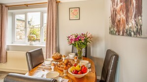 Un coin repas avec une table mise pour le petit-déjeuner, comprenant du pain, des œufs et des fruits.