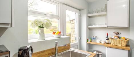 A modern kitchen with a built-in sink, a coffee maker, and a window with a vase of flowers.