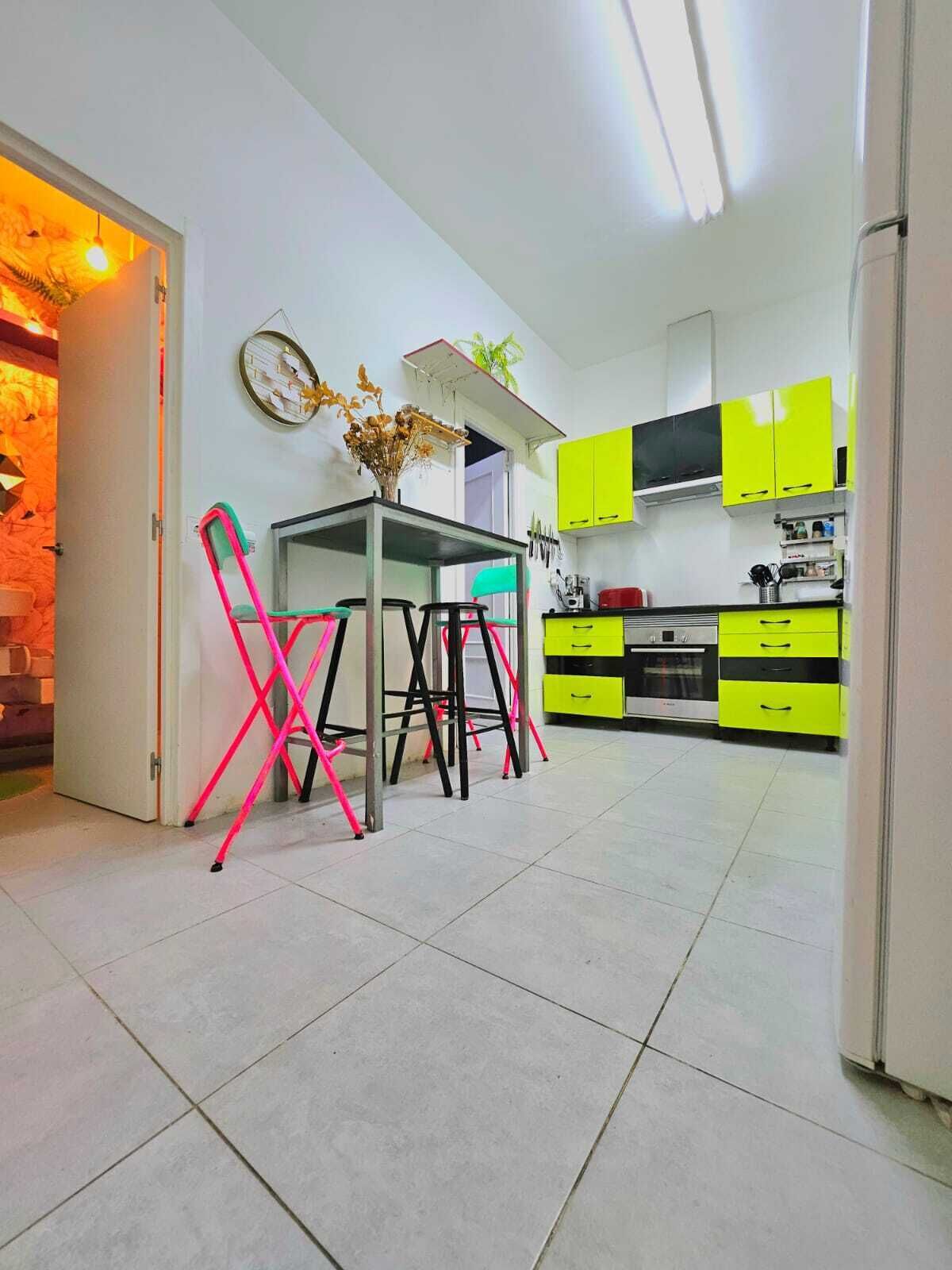 Een moderne keuken met heldergele kastjes, een eettafel met stoelen en een zichtbare oven.