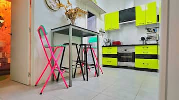 Een moderne keuken met heldergele kastjes, een eettafel met stoelen en een zichtbare oven.