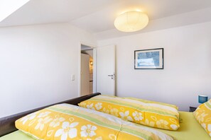 A bedroom with a bed, a door leading to another room, a framed picture on the wall, and a ceiling light fixture. - Apartment 'Haus Wohlfühlen' with Balcony and Air Conditioning (Ascheberg)
