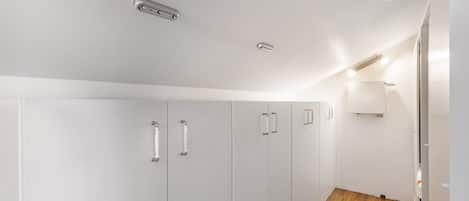A modern room with white walls, a wooden floor, and built-in wardrobes.
