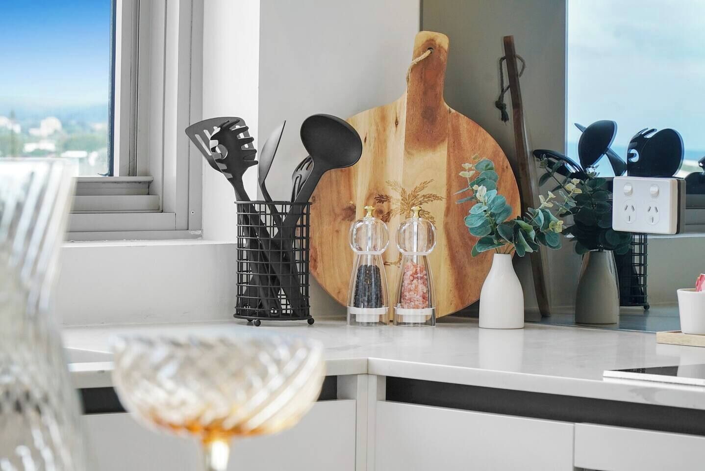 A kitchen counter with a wooden cutting board, a spice rack, and a potted plant.
