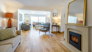 A living room with a fireplace, a sofa, a chair, and a lamp. - 3 Bed in Holt (oc-s40247) (Holt)