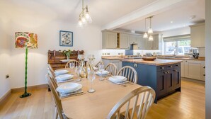 A modern kitchen with a central island, wooden dining table, and pendant lighting. - 3 Bed in Holt (oc-s40247) (Holt)